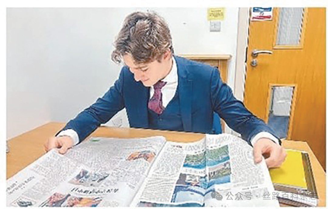 格列布在阅读刊登有自己文章的《人民日报海外版》.png
